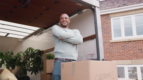 Portrait-Of-Man-Unloading-Boxes-From-Removal-Truck-Outside-New-Home-On-Moving-Day
