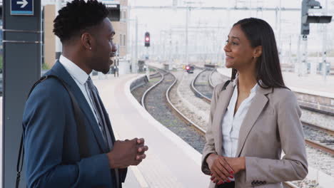 Businessman-And-Businesswoman-Commuting-To-Work-Talking-On-Railway-Platform-Waiting-For-Train