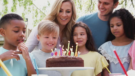 Parents-With-Son-Celebrating-Birthday-With-Friends-Having-Party-In-Garden-And-Blowing-Out-Candles