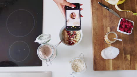 Overhead-Shot-Of-Woman-Taking-Picture-Of-Healthy-Breakfast-On-Mobile-Phone-At-Home-After-Exercise
