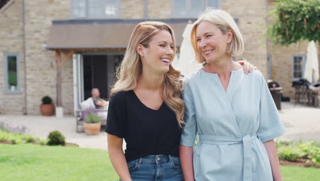 Senior-Mother-With-Adult-Daughter-Walking-And-Talking-In-Garden-Together