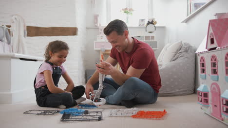 Padre-E-Hija-En-El-Dormitorio-Construyendo-Un-Kit-De-Robot-Juntos