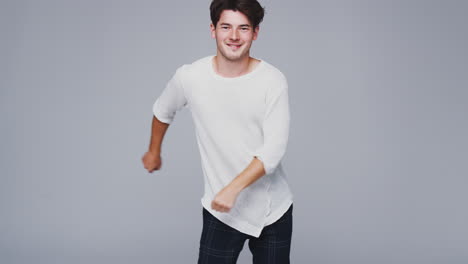 Wide-Angle-Studio-Shot-Of-Young-Man-Against-White-Background-Dancing-And-Flossing-In-Slow-Motion