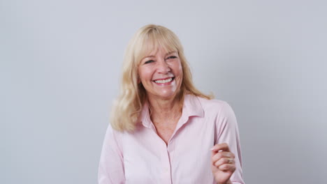 Studio-Shot-Of-Mature-Woman-Against-White-Background-Dancing-And-Laughing-At-Camera