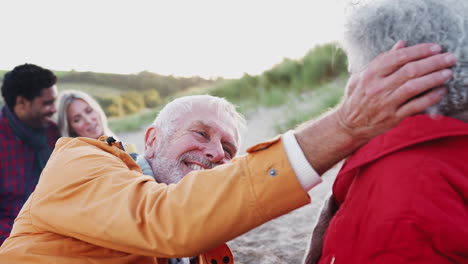 Liebevolles-Seniorenpaar-Entspannt-Sich-Am-Feuer-Mit-Erwachsenem-Nachwuchs-Im-Winterlichen-Strandurlaub