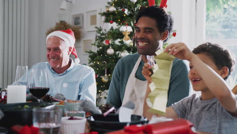 Father-With-Son-And-Grandfather-At-Dining-Table-Enjoying-Christmas-Meal-At-Home-Together