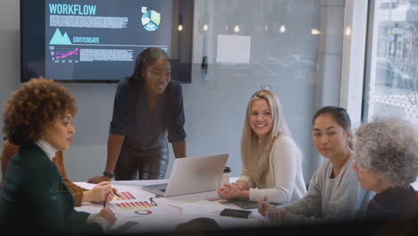 Blick-Durch-Das-Glas-Auf-Geschäftsfrauen,-Die-Bei-Kreativen-Treffen-Am-Tisch-Im-Modernen-Büro-Zusammenarbeiten