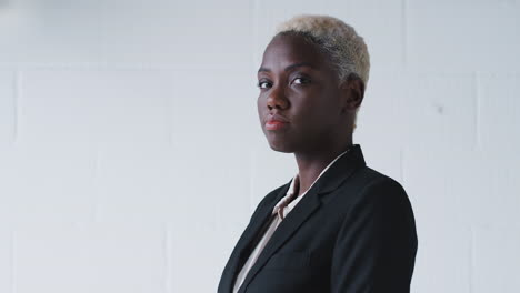 Portrait-Of-Determined-Young-Businesswoman-Wearing-Suit-Standing-Against-White-Studio-Wall
