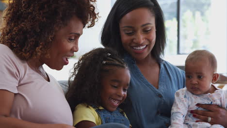 Multi-Generation-Female-African-American-Family-Sitting-On-Sofa-At-Home-Using-Digital-Tablet