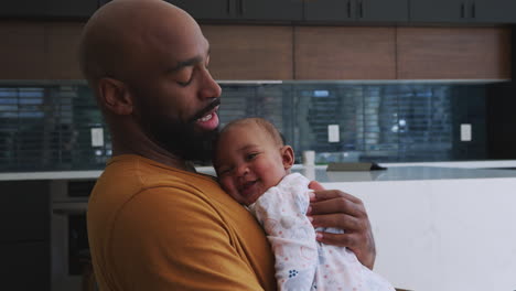 Smiling-African-American-Father-Cuddling-And-Playing-With-Baby-Daughter-Indoors-At-Home