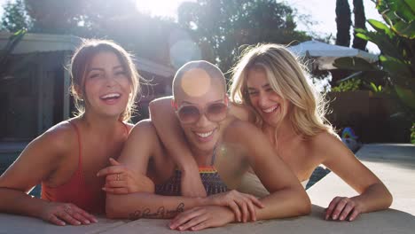 Portrait-Of-Three-Female-Friends-Outdoors-Relaxing-In-Swimming-Pool-And-Enjoying-Summer-Pool-Party