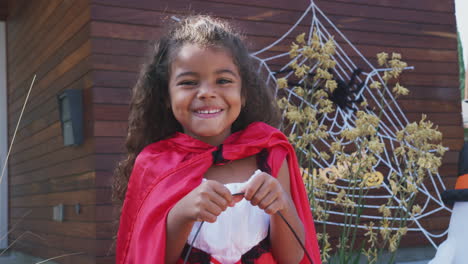 Portrait-Of-Young-Girl-Wearing-Fancy-Dress-Outside-House-Collecting-Candy-For-Trick-Or-Treat