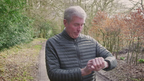 Senior-Man-Running-In-Countryside-Exercising-Checking-Smart-Watch-Fitness-Activity-App