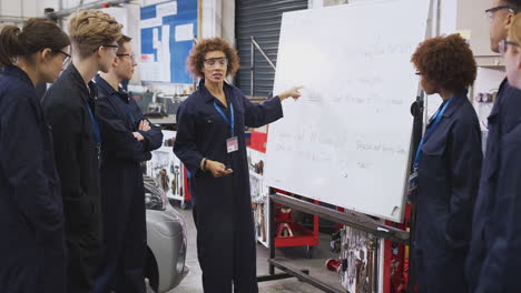 Female-Tutor-By-Whiteboard-With-Students-Teaching-Auto-Mechanic-Apprenticeship-At-College