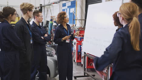 Students-Studying-Auto-Mechanic-Apprenticeship-At-College-Asking-Female-Tutor-Questions
