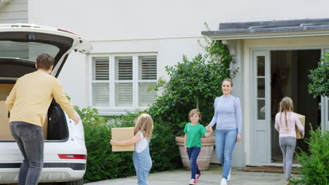 Family-Outside-New-Home-On-Moving-Day-Unloading-Boxes-From-Car