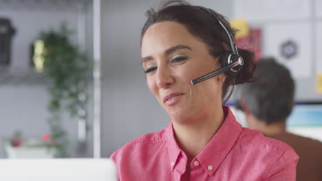 Businesswoman-Wearing-Telephone-Headset-Talking-To-Client-In-Customer-Services-Call-Centre