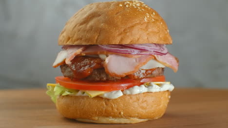 Yummy-fast-food-concept.-Fresh-homemade-grilled-burger-with-meat-patty-tomatoes-cucumber-lettuce-onion-and-sesame-seeds.-Unhealthy-lifestyle.-Food-background.