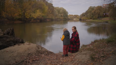 Viaje-Familiar-En-El-Bosque-La-Madre-Y-El-Niño-Descansan-En-La-Costa-Del-Lago-Del-Bosque-Jugando-Y-Divirtiéndose-Juntos-Infancia-Feliz-Con-Mamá