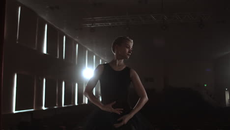 La-Compañía-De-Ballet-Prima-Con-Un-Vestido-Oscuro-En-Un-Escenario-De-Teatro-Oscuro-Ensayando-Entre-El-Humo-Realiza-Movimientos-De-Baile-En-Cámara-Lenta.