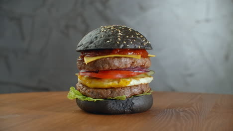 Hamburguesa-Negra.-Una-Hamburguesa-Con-Un-Panecillo-Negro,-Rebanadas-De-Jugosa-Carne-De-Res-Mármol,-Queso-Fundido,-Ensalada-Fresca-Y-Salsa-De-Barbacoa.