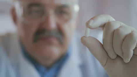 Doctor-holds-a-pill-in-his-hands-and-looks-at-the-camera-close-up.-High-quality-4k-footage