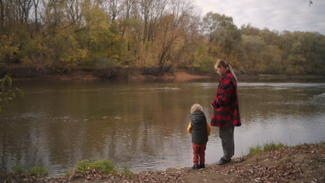 weekend-on-shore-of-forest-lake-at-autumn-young-mother-with-her-baby-are-viewing-birds-spending-time-together-with-family-happy-motherhood-and-childhood