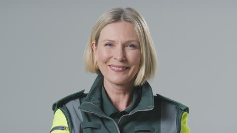Studio-Portrait-Of-Smiling-Mature-Female-Paramedic-Against-Plain-Background