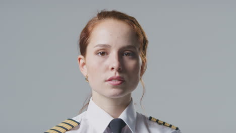 Studio-Portrait-Of-Serious-Female-Airline-Pilot-Or-Ship-Captain-Against-Plain-Background