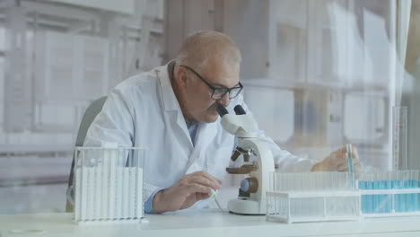 Científico-Investigador-Masculino.-Está-Sentado-En-Un-Laboratorio-Moderno-De-Alta-Gama-Con-Un-Microscopio-De-Cristalería-Y-Monitores-De-Trabajo-A-Su-Alrededor.-Imágenes-4k-De-Alta-Calidad