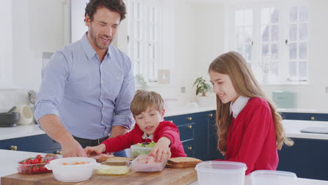Padre-Ayudando-A-Niños-Con-Uniforme-Escolar-A-Preparar-Un-Sándwich-Saludable-Para-El-Almuerzo-Para-Llevar-En-La-Cocina