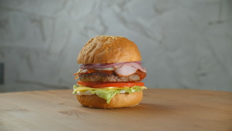 Yummy-fast-food-concept.-Fresh-homemade-grilled-burger-with-meat-patty-tomatoes-cucumber-lettuce-onion-and-sesame-seeds.-Unhealthy-lifestyle.-Food-background.