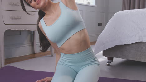 Woman-doing-yoga-stretching-sitting-on-exercise-mat-in-bedroom-at-home----shot-in-slow-motion