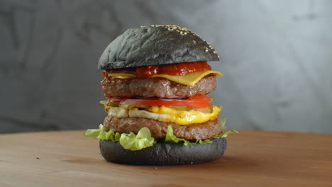 Hamburguesa-Negra.-Una-Hamburguesa-Con-Un-Panecillo-Negro,-Rebanadas-De-Jugosa-Carne-De-Res-Mármol,-Queso-Fundido,-Ensalada-Fresca-Y-Salsa-De-Barbacoa.