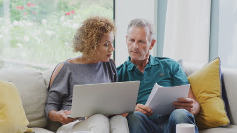 Ein-älteres-Ehepaar-Im-Ruhestand-Sitzt-Zu-Hause-Auf-Dem-Sofa-Und-überprüft-Seine-Persönlichen-Finanzen-Auf-Dem-Laptop