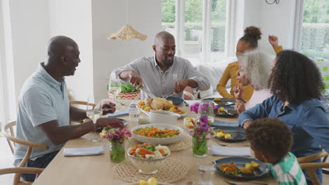 Father-Carving-As-Multi-Generation-Family-Sit-Around-Table-At-Home-And-Enjoy-Eating-Meal
