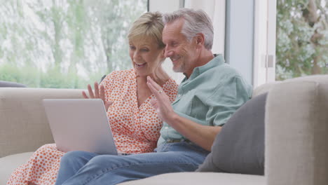 Älteres-Ehepaar-Im-Ruhestand-Sitzt-Zu-Hause-Auf-Dem-Sofa-Und-Führt-Videoanrufe-Auf-Dem-Laptop-Durch