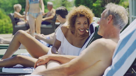 Älteres-Ehepaar-Im-Ruhestand-Auf-Liegestühlen,-Die-Sich-Im-Sommerurlaub-Am-Pool-Entspannen