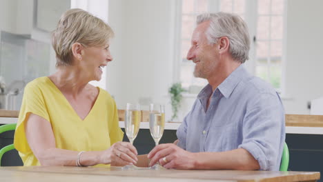 Küssendes-Rentnerehepaar,-Das-Zu-Hause-Am-Gemeinsamen-Date-Abend-Mit-Einem-Glas-Champagner-Feiert