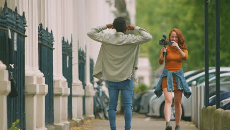 Pareja-Joven-Viajando-Juntos-Por-La-Ciudad-Haciendo-Vlogging-Con-Una-Cámara-De-Video-En-Un-Trípode