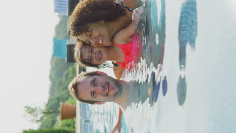 Vertical-Video-Portrait-Of-Multi-Racial-Family-Relaxing-In-Swimming-Pool-On-Summer-Vacation-Together