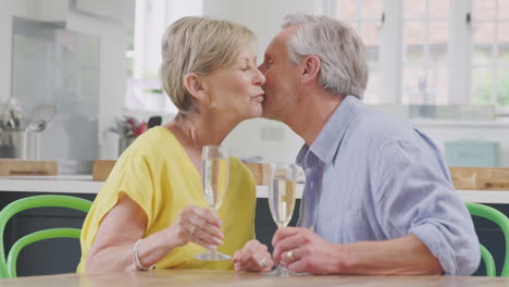 Küssendes-Rentnerehepaar,-Das-Zu-Hause-Am-Gemeinsamen-Date-Abend-Mit-Einem-Glas-Champagner-Feiert