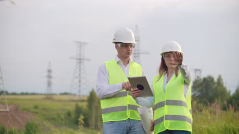 Ingenieros-Uniformados-Trabajando-Con-Una-Computadora-Portátil-Cerca-De-Líneas-De-Transmisión.