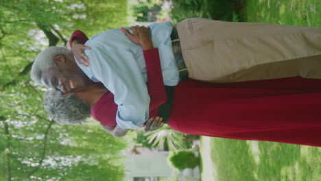 Vertical-Video-Of-Loving-Senior-Couple-Standing-In-Garden-At-Home-And-Hugging-After-Retirement