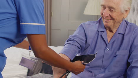 Close-Up-Of-Senior-Man-At-Home-In-Bed-Having-Blood-Pressure-Taken-By-Female-Care-Worker-In-Uniform
