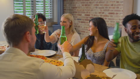 Eine-Multikulturelle-Gruppe-Von-Freunden-Stößt-An,-Während-Sie-Zu-Hause-Gemeinsam-Bier-Und-Pizza-Genießt