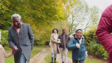 Smiling-multi-generation-family-walking-through-autumn-countryside-together-with-grandchildren-running-ahead---shot-in-slow-motion