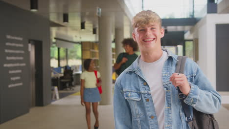 Portrait-Of-Smiling-Male-Student-In-Busy-University-Or-College-Building