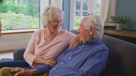 Liebevolles-Seniorenpaar,-Das-Seinen-Ruhestand-Genießt,-Sitzt-Zu-Hause-Auf-Dem-Sofa-Und-Redet-Und-Lacht-Zusammen