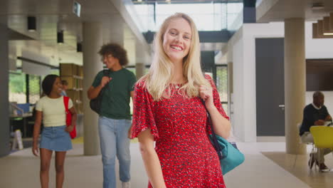 Portrait-Of-Smiling-Female-Student-In-Busy-University-Or-College-Building